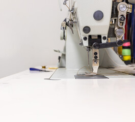 A professional sewing machine is in the workshop. Against the background of various devices and what a seamstress needs for work-knickknacks and tools. High quality photo