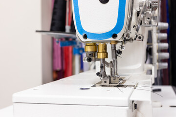 A professional sewing machine is in the workshop. Against the background of various devices and what a seamstress needs for work-knickknacks and tools. High quality photo
