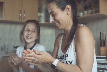 Mom and daughter have fun in the kitchen and cook together. Joyful and beautiful. High quality photo
