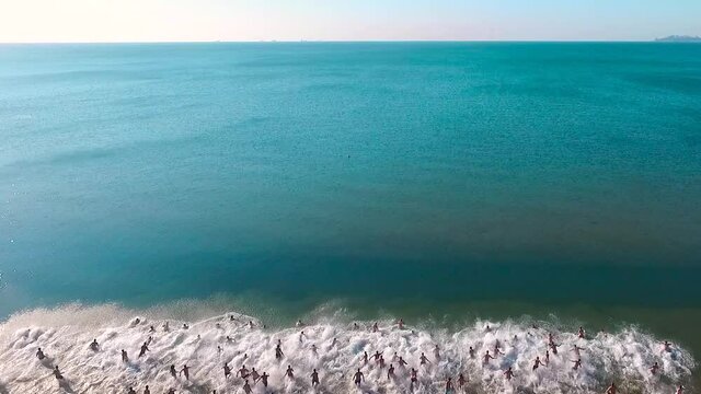 More than two hundred people at the same time dive into the sea. People rejoice that quarantine related to the COVID-19 pandemic has been completed and beaches are open. Aerial view
