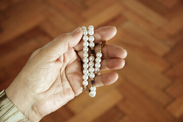 Hands of adult woman praying with a rosary