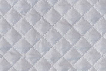 Checkered texture of white fabric with diagonal mesh embossing. Abstract material pattern or background. Close up shot.