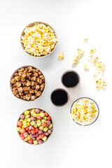 Set of flavored popcorn and soda on white table top-down