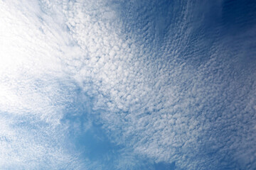 Blue sky covered with white cirrus clouds. Summer cloudscape, beautiful weather background