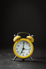 Yellow vintage alarm clock on the black background. shallow depth of field
