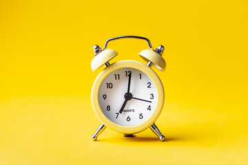 Yellow vintage clock on the yellow background with copy space