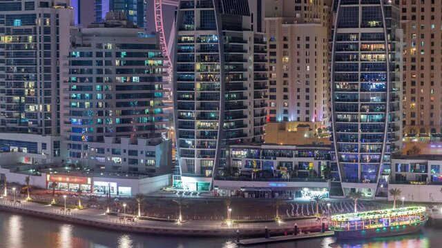 Dubai Marina after sunset with skyscrapers and promenade aerial day to night transition timelapse. Modern towers and boats from above, port with luxury yachts. United Arab Emirates