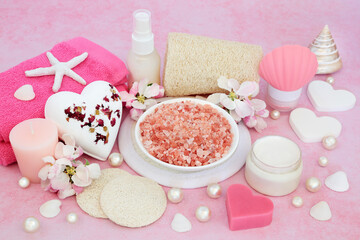 Beauty treatment for skincare with Himalayan ex foliation mineral salts, spa, massage and cleansing products with apple blossom flowers on pink background.
