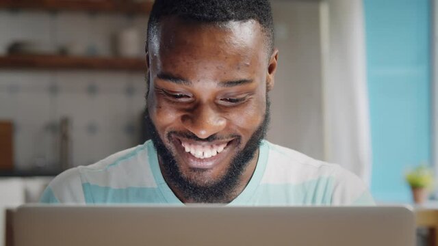 Excited african man using laptop and doing winner gesture at home