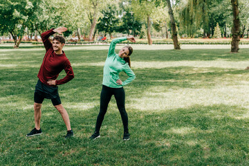 Handsome man smiling while working out near beautiful girlfriend in park