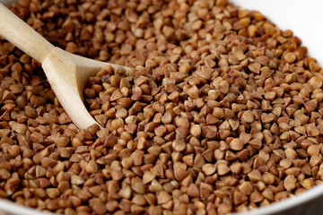 Bowl of raw uncooked buckwheat on wooden table