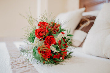 Wedding bouquet with red roses before the ceremony  on the bed of the bride