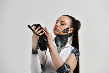 beautiful brunette girl in a robot suit is studying an old receiver that plays music