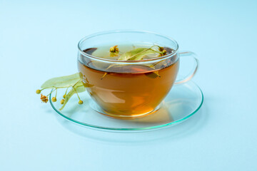Cup of linden tea on blue background, close up