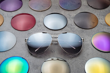 Fashion sunglasses and different multicolored lenses on table in eyeglasses optical store, fashion...