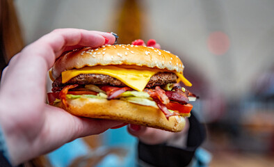 Woman hand is holding a fresh burger before eating on street