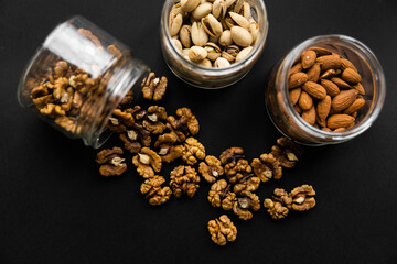 Walnut scattered on the black table from a jar. Walnut is a healthy vegetarian protein nutritious food.