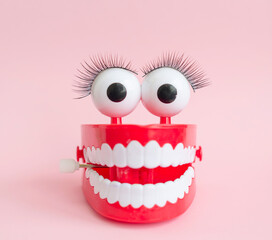 toy with smiling teeth and eyes on pink background as a concept of dentistry and healthy oral cavity and smile