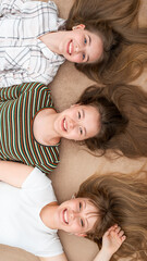 group of cheerful young girlfriends with long hair lying in a row, top view