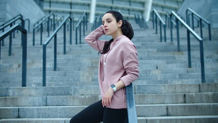 Fitness woman relaxing on staircase outdoor. Young female model posing on stairs