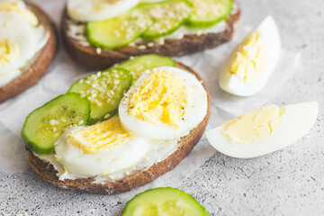 Sandwiches with egg, cucumber, sesame seeds and spices. Tasty breakfast. Sandwiches on the table