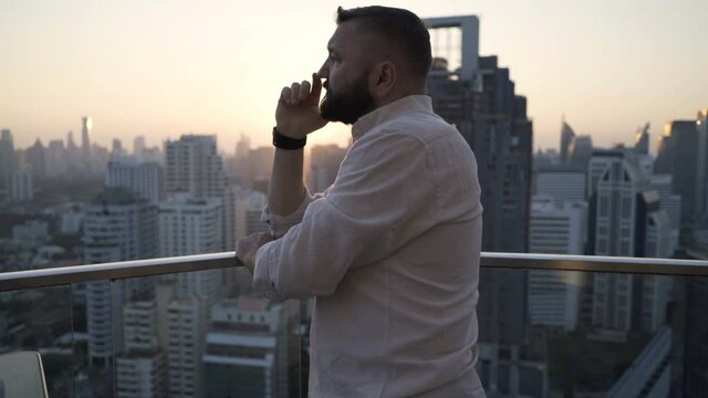 Pensive, thoughtful man admire city, standing on terrace during sunset