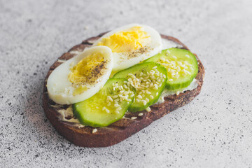Sandwich with egg, cucumber, sesame seeds and spices. Tasty breakfast. Sandwich on the table