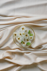 Ice cubes with flowers on silk. Fashion photography.
