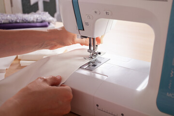 The seamstresses are stale on the sewing machine details of clothing made of fabric. The master sews new clothes on the sewing machine. A woman makes wardrobe details with her own hands. Business