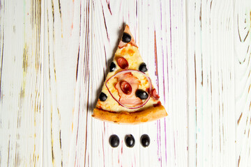 Top view of traditional Italian pizza with ham, sausages, red onion, olives, cheese and tomato sauce on light wooden background. Black olives near Tasty Slice of pizza. Delicious Mediterranean meal