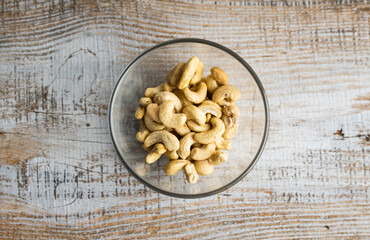 Cashew nuts in a small plate on a vintage wooden table as a background. Cashew nut is a healthy vegetarian protein nutritious food.