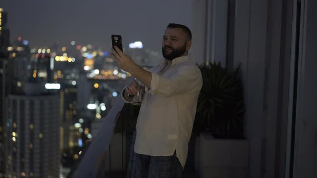Young man with beer taking selfie photo with cellphone on terrace