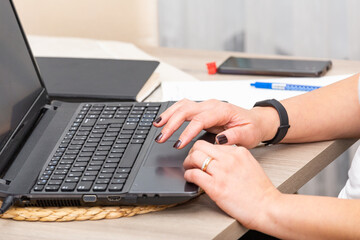Close up of a woman working with a laptop at home with touching pad.