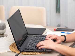 Close up of a woman working with a laptop at home and using keyboard.