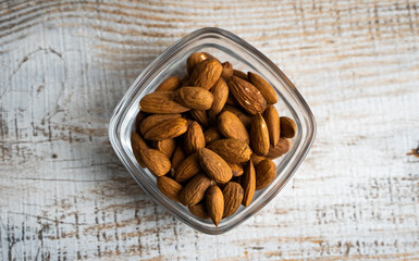 Almonds in a small plate on a vintage wooden table. Almond is a healthy vegetarian protein nutritious food. Natural nuts snacks.