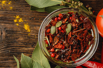 Red chili spice in glass bowl with herbs on dark table