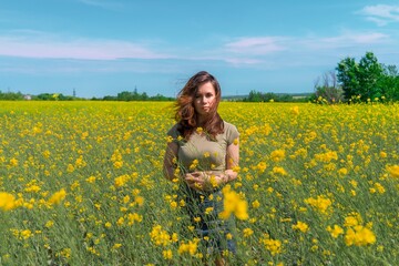 Naklejka na ściany i meble A girl with long hair walks in a yellow rapeseed field