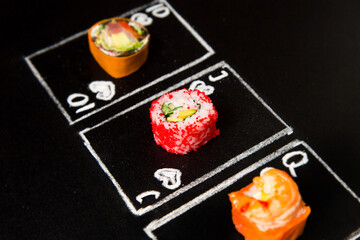 Hand drawn Poker cards with Japanese sushi roll pieces on dark chalkboard background. Asian rolls with carrot, shrimp, salmon, avocado and flying fish roe. Ten, Jack and Queen of Hearts chalk cards
