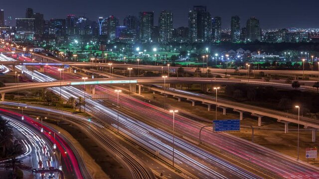 Dubai Golf Course with a cityscape of Gereens and tecom districts at the background aerial day to night transition timelapse. Traffic on sheikh zayed road with junction