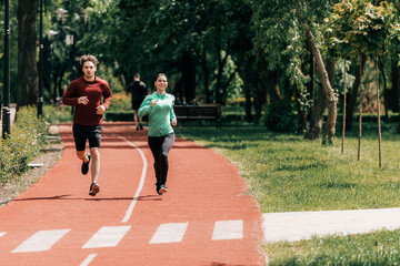 Smiling woman running near handsome boyfriend on running track in park