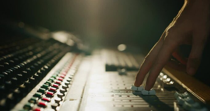 Close up slide shot of a sound producer hand is using a music mixer with editing tools in a professional recording studio.