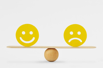 Smiley face and sad face on scale - Concept of balance between happiness and sadness