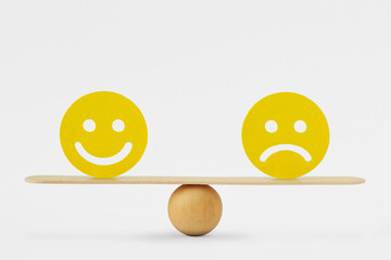 Smiley face and sad face on scale - Concept of balance between happiness and sadness