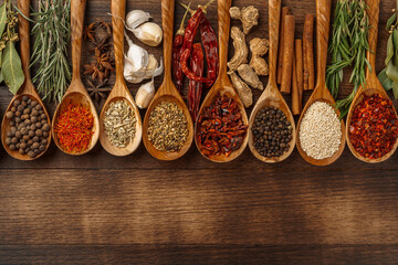Vivid colorful spices in wooden spoons on wooden background