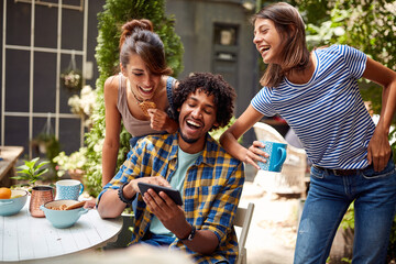 Young guy showing funny content of mobile to his friends