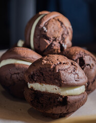 Broken cookies and stack of sponge cookies with cream on paper.