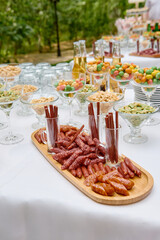 Assorted sausages on wood board on luxury wedding reception outdoors, copy space. Street food market