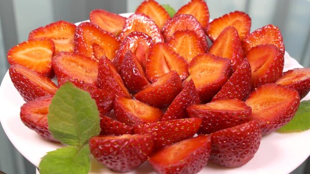 Strawberries on a silver platter. Dessert dish made from slices of strawberries and sprigs of mint. Serving dessert in a restaurant.