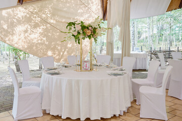Table setting with white plate with napkin, cutlery and flowers on table, copy space. Place setting at wedding reception. Table served for banquet in restaurant