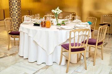 Table setting with blank guest card, plates with napkins and cutlery, copy space. Place setting at wedding reception. Round table served for banquet in restaurant